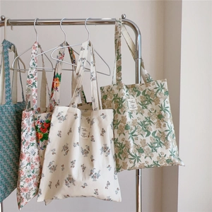 Vue détaillée de sacs cabas en toile de coton aux motifs floraux sur un support