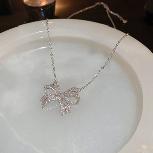 Macro shot of silver bow pendant with micro-pave zircons on a white ceramic plate