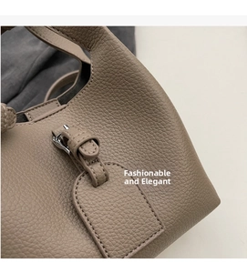 Détails de la texture du cuir litchi gris et boucle argentée sur le sac seau
