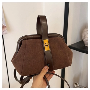 Detailed close-up of dark brown shell bag with matte suede texture and gold buckle