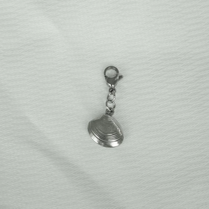 Detail of silver stainless steel shell pendant with lobster clasp on fabric texture