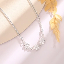 Close-up of triple flower pendants on silver chain necklace with elegant floral background