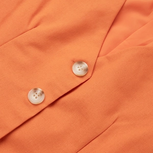 Detailed macro view of orange linen-cotton vest featuring marble texture buttons