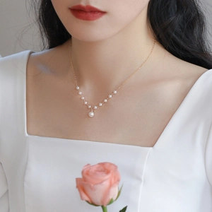 Elegant freshwater pearl necklace shown on a model with a gold chain and pendant
