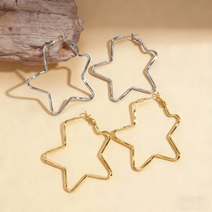 Minimalist hollow star hoop earrings in gold and silver finish on a wooden display