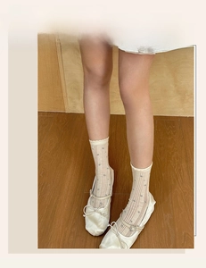 Close-up of beige crew socks with blue floral patterns and white satin Mary Jane shoes