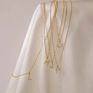 Close-up of golden pearl and rhinestone letter pendants on white satin fabric