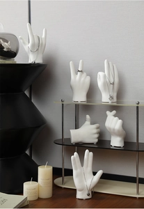 Matte white ceramic hand gesture jewelry stands for rings and necklaces on modern shelves