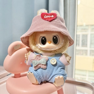 Labubu plush doll wearing pink corduroy hat and blue overalls on a pink chair
