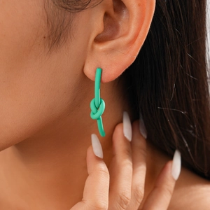 Dettaglio di orecchini a nodo verde menta opaco indossati da una modella elegante
