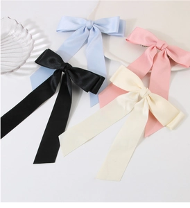 Flat lay of large silk ribbon bow hair clips in black, light blue, pink, and beige
