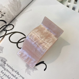 Detailed close-up of large pink pearlescent acetate hair claw clip on magazine