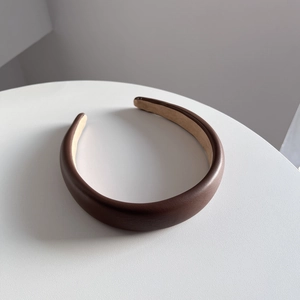 Macro detail of the premium dark brown PU leather headband texture with fine stitching