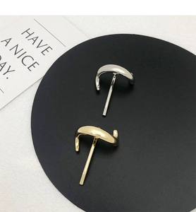 Close-up of minimalist streamlined curved metal hair clips in gold and silver finishes