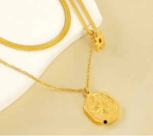 Detail of gold double-layer necklace with flat snake chain and starburst pendant