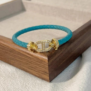 Dettaglio del bracciale in pelle intrecciata azzurra con fibbia CD dorata e cristalli