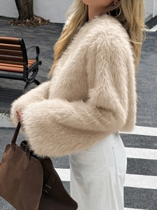 Dettaglio di un elegante cappotto in ecopelliccia beige da donna con pantaloni bianchi