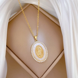 Detail of gold oval shell pendant with virgin Mary relief and white zircons