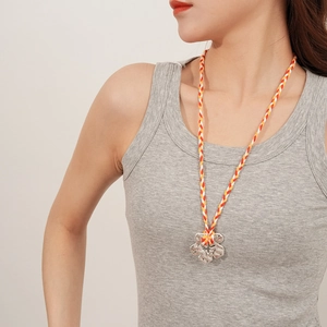 Detail of silver flower pendant on a tricolor woven cord necklace for women