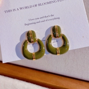 Detailed view of vintage dark green U-shaped enamel earrings with gold metal accents
