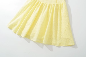 Détail de l'ourlet de robe jaune avec broderie anglaise et plis sophistiqués