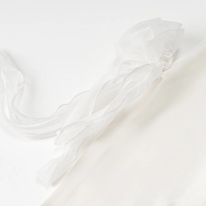 Detailed macro view of white translucent lace straps and textured fabric on a satin dress