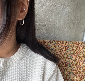 Detail showing minimalist 925 silver star studs and hoop earrings worn by a model