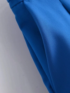 Macro de la textura de tela azul cobalto y costuras laterales limpias del pantalón de talle alto