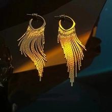 Detail of long golden tassel earrings with flowing metallic chains for a luxurious look