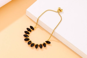 Detail of adjustable gold chain bracelet featuring black faceted beads and slider clasp