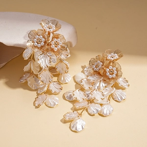 Detail of golden flower tassel earrings featuring pearl centers and dangling shell petals