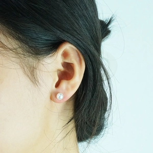 Pendientes de perlas clásicos de acero inoxidable de 18K usados por una modelo femenina