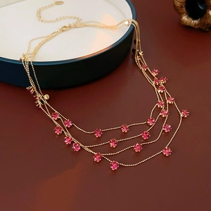 Détail d'un collier multi-rangs doré avec de petites pierres roses sur des chaînes fines
