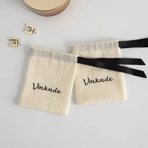 Detail of beige cotton jewelry drawstring pouch with black ribbon and Vinknde logo