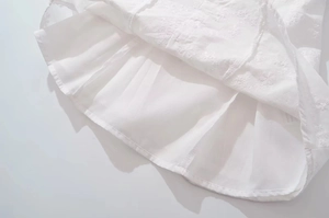Detailed close-up of intricate white floral embroidery on a double-layered lace dress