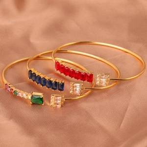 Macro-opname van verstelbare gouden open armbanden met gekleurde zirkoon op zijden stof