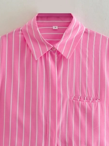 Détail d'un col de chemise à rayures roses et blanches avec boutonnière et poche poitrine