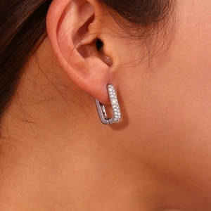 Detailed view of silver geometric rectangular earrings with inlaid zircons on model ear