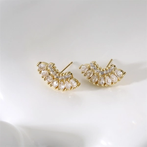 Détail des boucles d'oreilles dorées en éventail serties de zircons blancs poires
