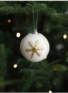 Close-up of white flocked Christmas ball with gold embroidered snowflake on festive tree
