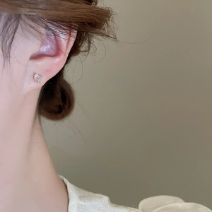 Close-up of a silver butterfly earring with pearlescent wings on model's ear