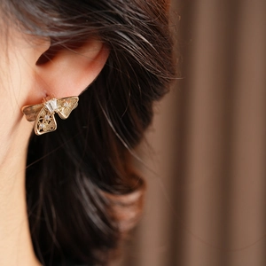 Détail d'une boucle d'oreille papillon ajourée avec cristaux portées par un mannequin