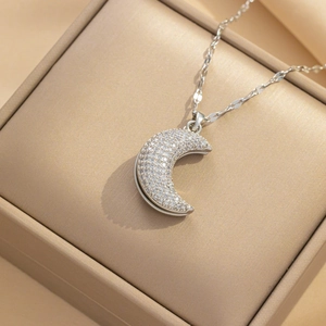 Silver crescent moon necklace with sparkling crystals on beige silk jewelry box