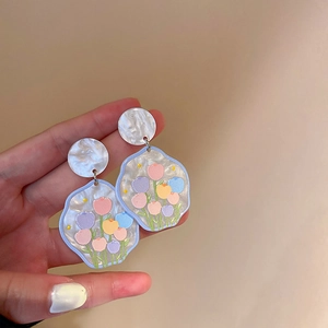 Détail de boucles d'oreilles tulipes en acrylique blanc nacré aux motifs pastel