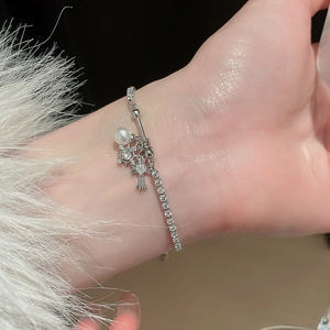 Macro view of adjustable silver zircon bracelet with cross charm and white pearl