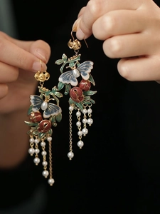 Détail de boucles d'oreilles papillon vintage en émail avec glands de perles longs