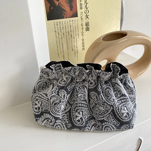 Detail of dark grey paisley embroidered drawstring pouch with lace trim and pearl accents