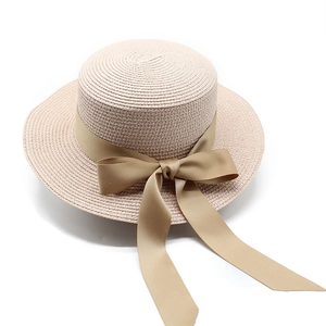 Dettaglio ravvicinato di un cappello di paglia beige con nastro e fiocco color kaki