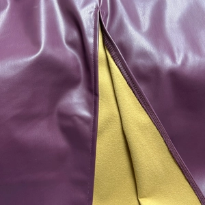Dettaglio della gonna in finta pelle viola con fodera in pile giallo e cuciture sullo spacco