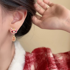 Detail of red lion dance earrings with Zhaocai lucky charm on model's ear